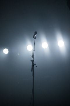 Black background with a microphone on a stand with spotlight shining down onto the mic.