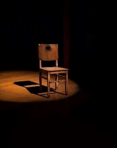 A lone, empty chair in a spotlight.